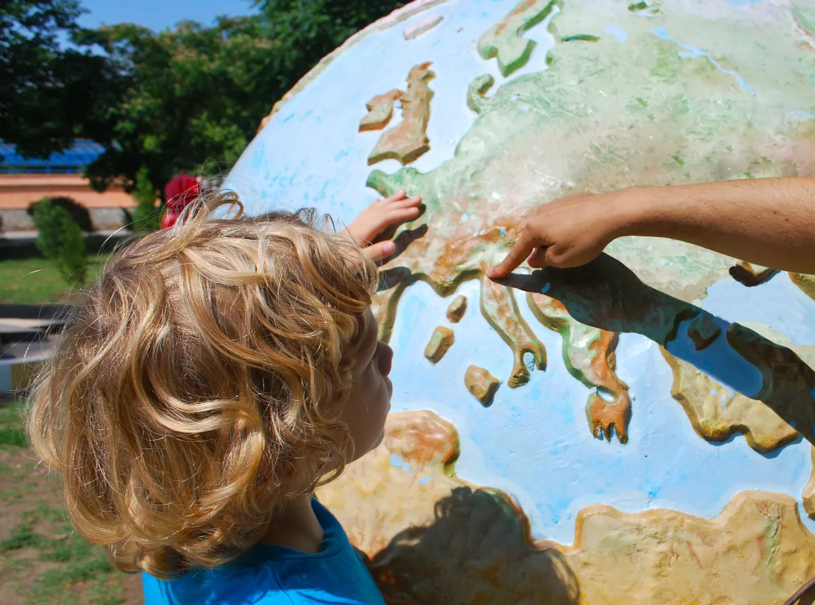 About us - kid pointing at Italy on a globe